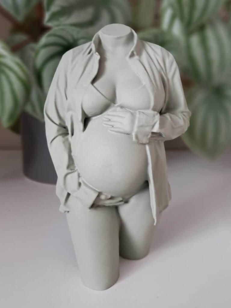 Lichtgroen 3D-zwangerschapsbeeldje met open blouse en handen rond de buik, voor groene kamerplanten.